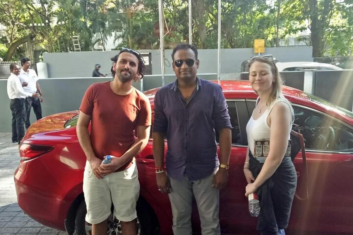 sekumpulan tiga orang berdiri di sebelah kereta merah