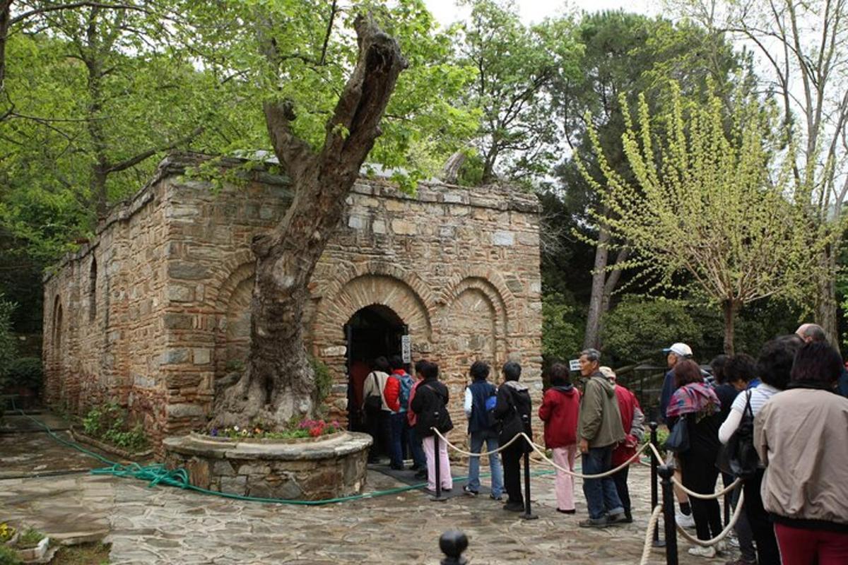 a group of people standing around a stone wall with a tree