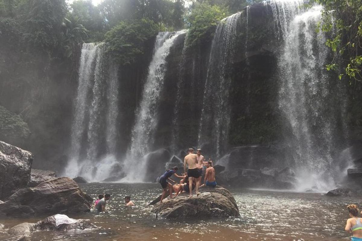 група людей, що стоять у воді біля водоспаду