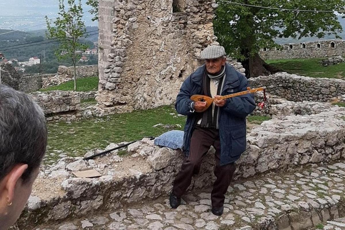 a man standing on a stone wall playing an instrument