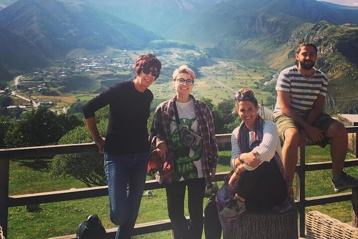 en gruppe mennesker som sitter på et gjerde foran et fjell
