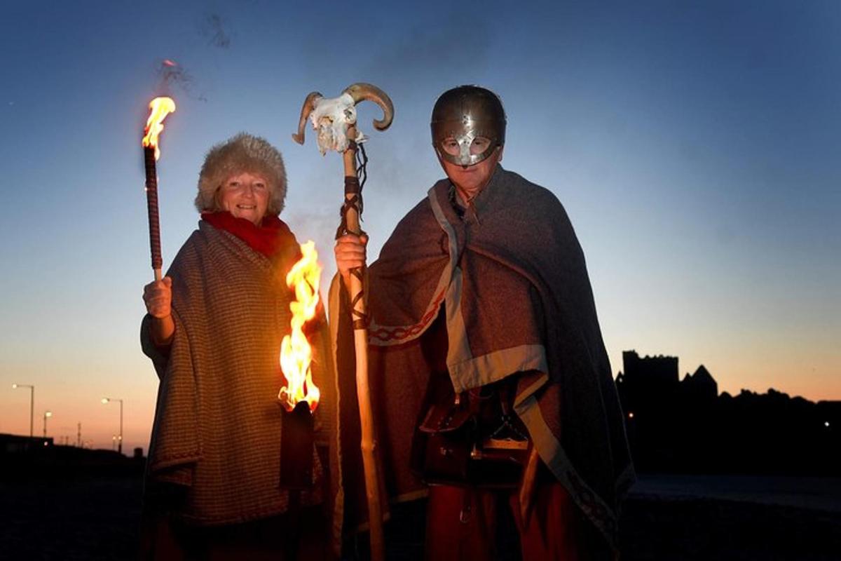 a man and a woman dressed in armor holding torches