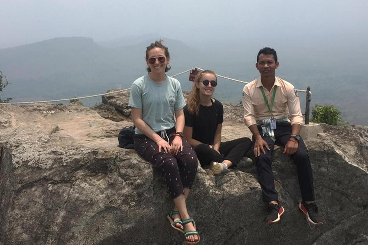 tre persone sedute sul bordo di una montagna