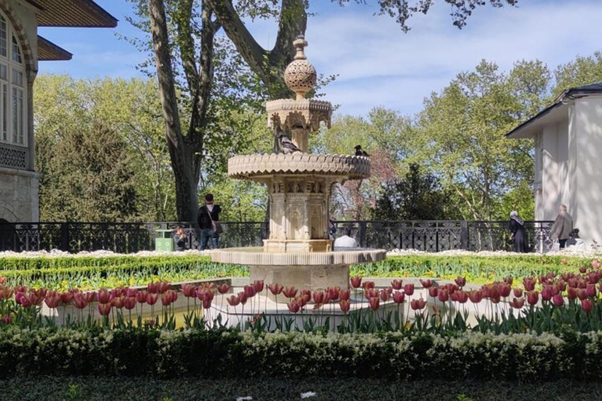 una fontana in un giardino con tulipani rossi e bianchi