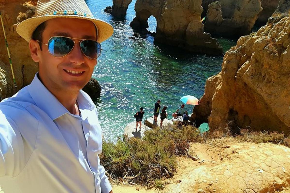 a man wearing a hat and sunglasses next to a body of water