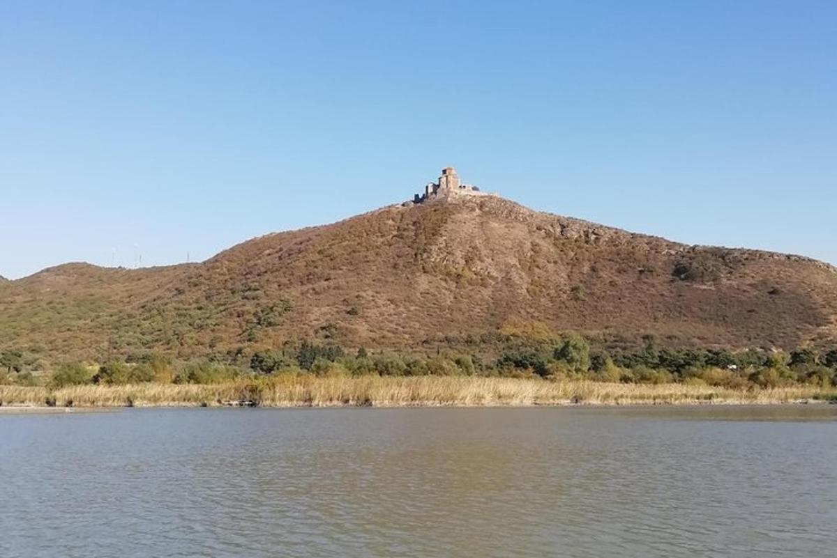 a hill with a house on top of it next to a body of water