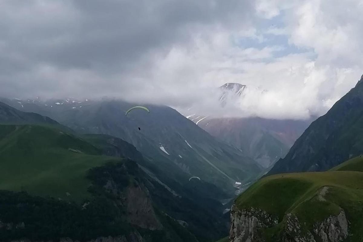 una persona que fa volar un estel en una vall de muntanya