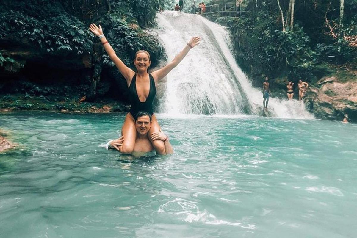 a woman in the water in front of a waterfall