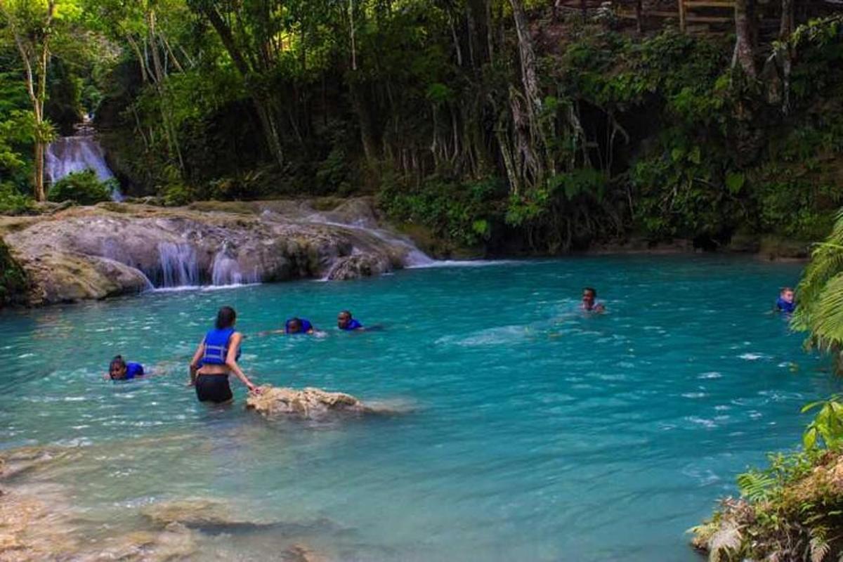 a woman standing in the water near a waterfall
