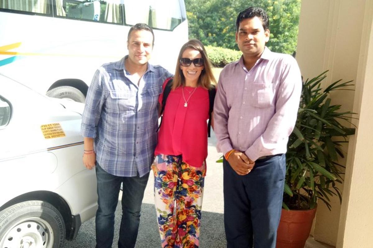 Una mujer y dos hombres de pie junto a un coche blanco.