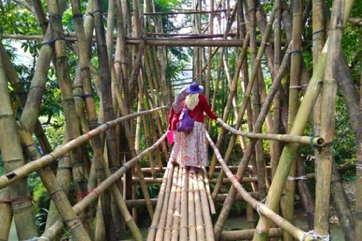 một người phụ nữ đang đi qua một cây cầu tre