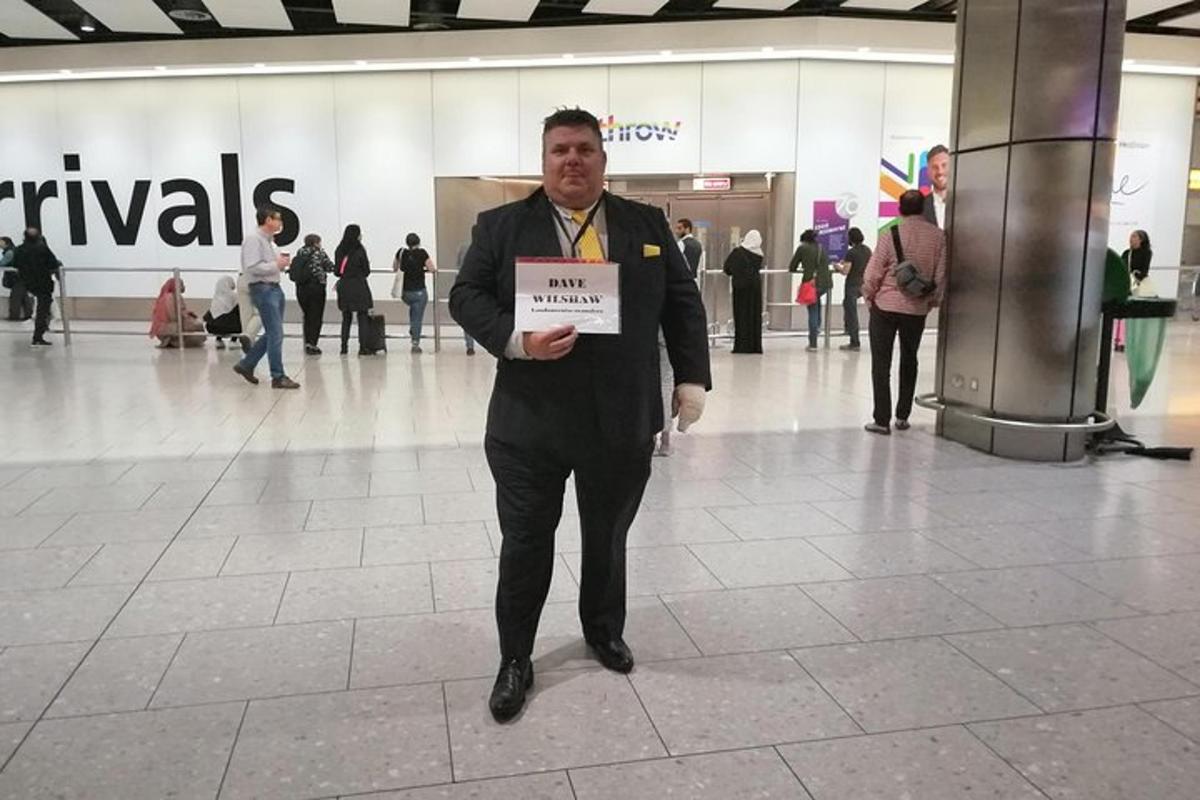 un uomo in giacca e cravatta che tiene un cartello in un centro commerciale