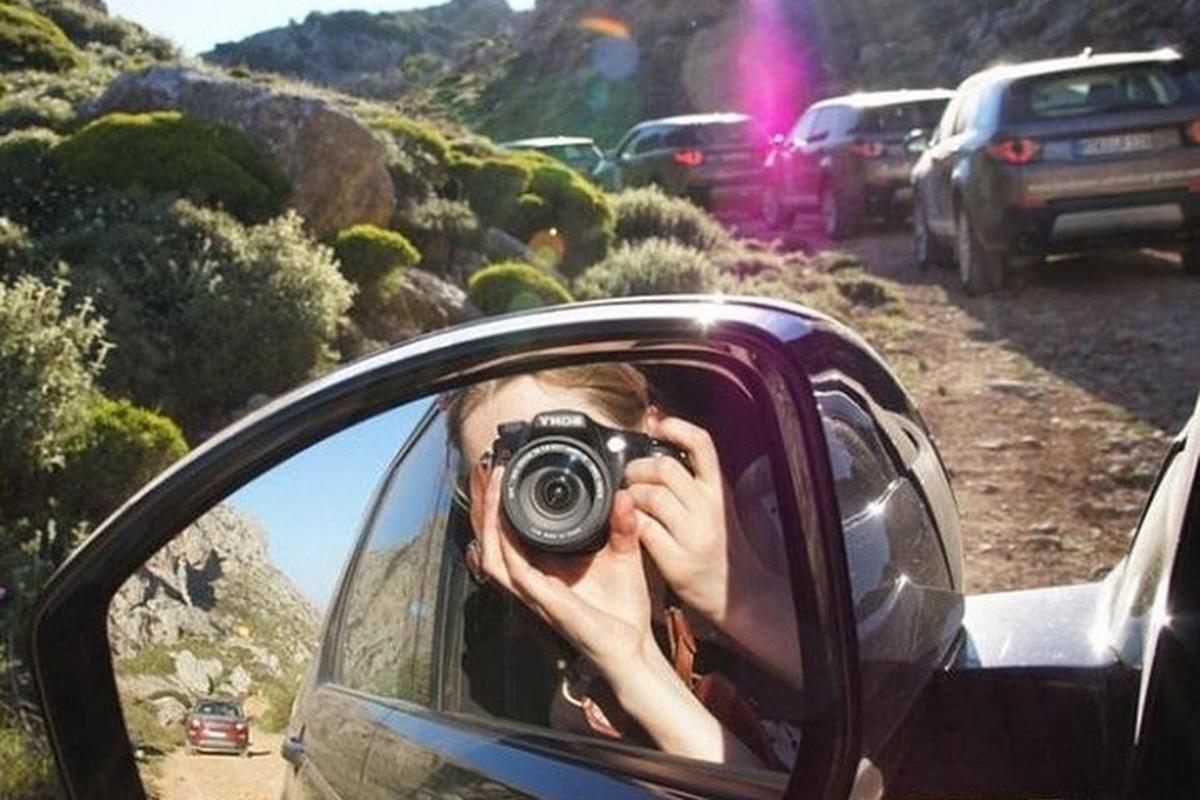 ženska, ki fotografira avtomobil v vzvratnem ogledalu