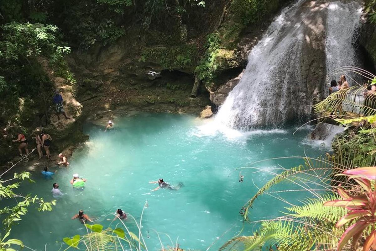 orang berenang di kolam di hadapan air terjun