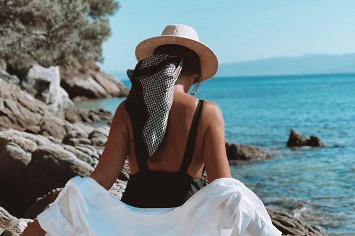žena sedící na pláži a dívající se na vodu