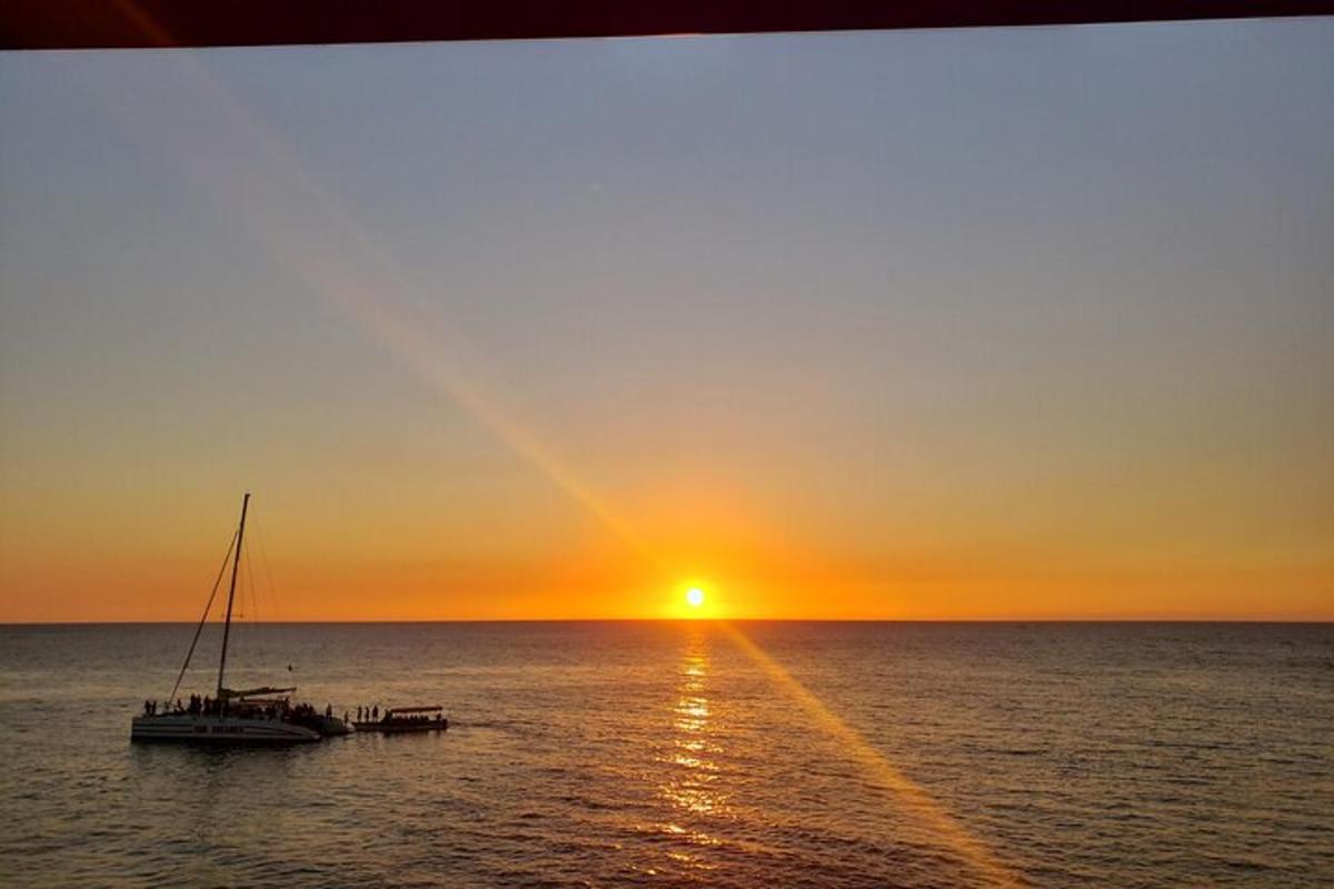 um barco no oceano com o pôr do sol ao fundo