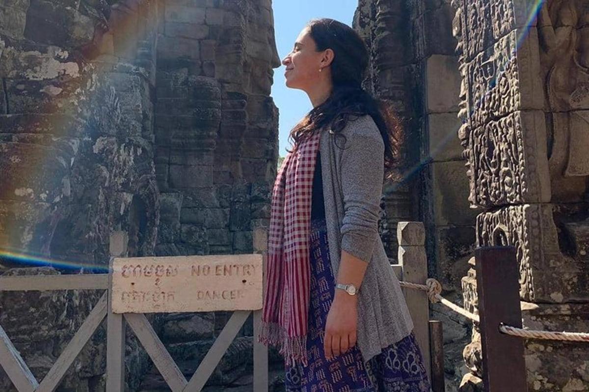 Una mujer parada junto a una pared con un arcoíris.