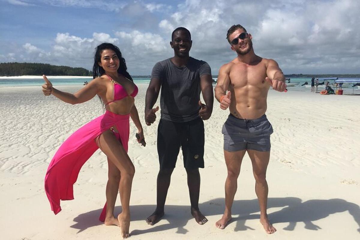 een groep van drie mensen die op een strand staan