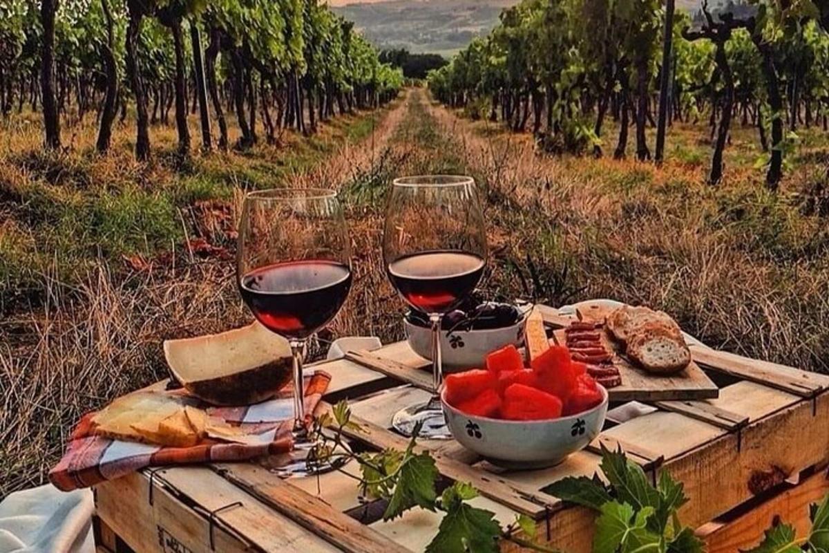 a table with two glasses of wine and a bowl of fruit
