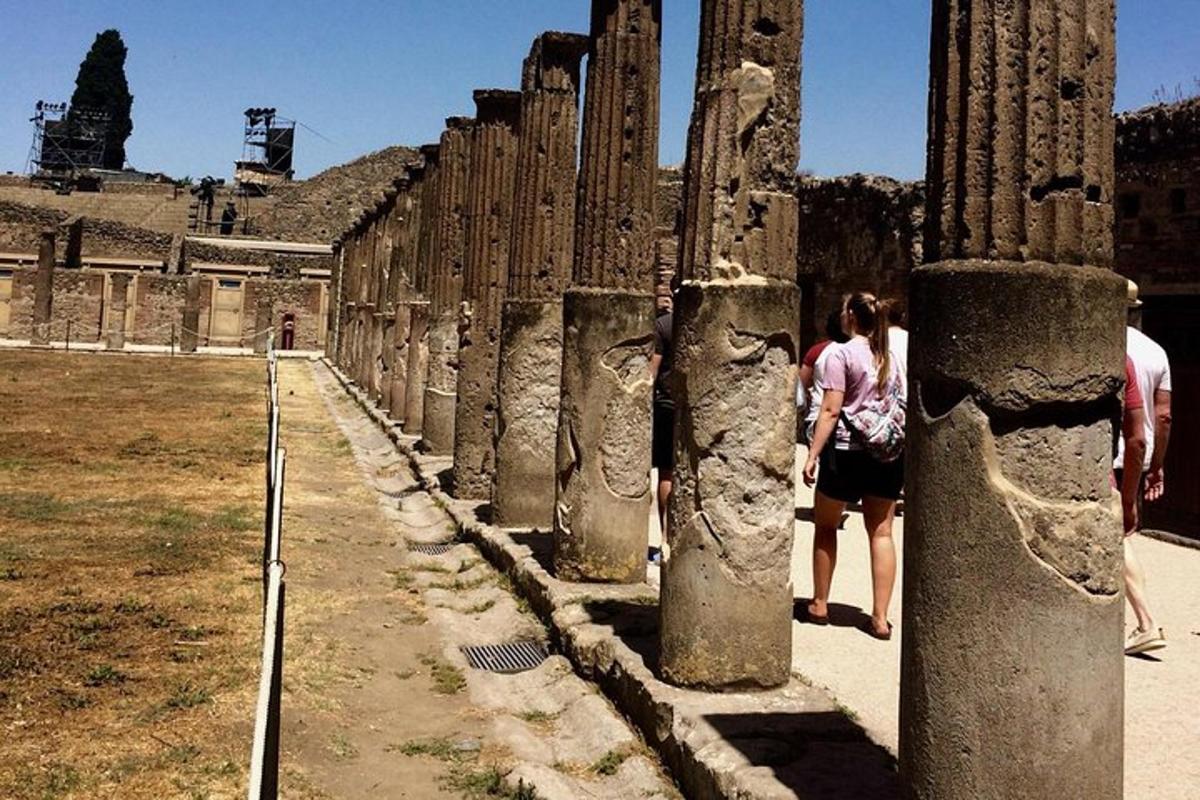 a woman standing next to a row of pillars