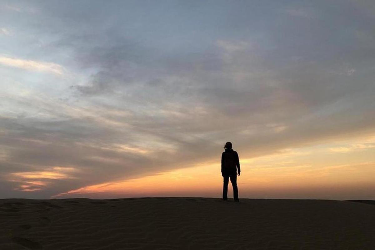 a person standing on top of a hill with the sunset