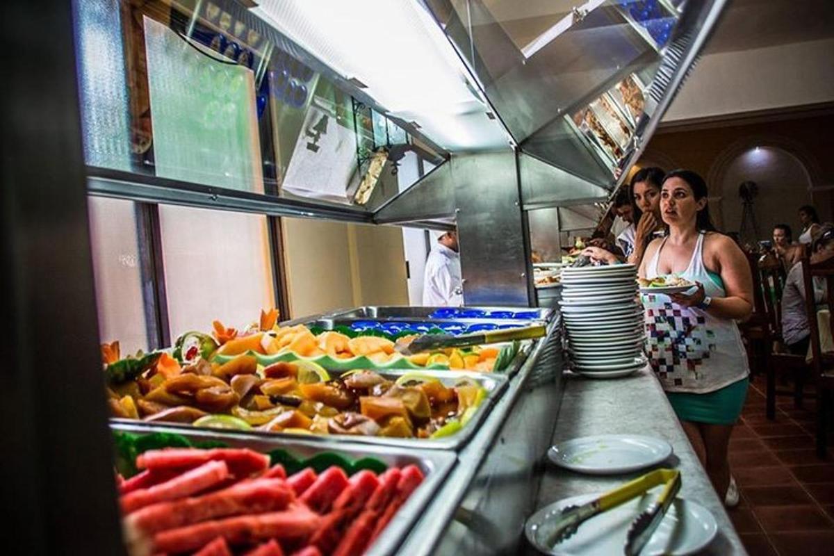 seorang wanita berdiri di hadapan barisan bufet dengan makanan