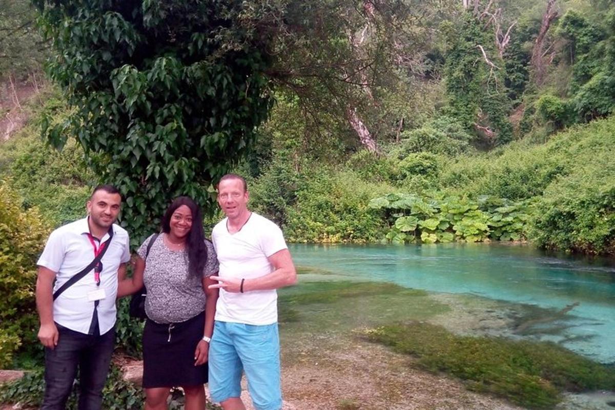 a group of three people standing next to a river