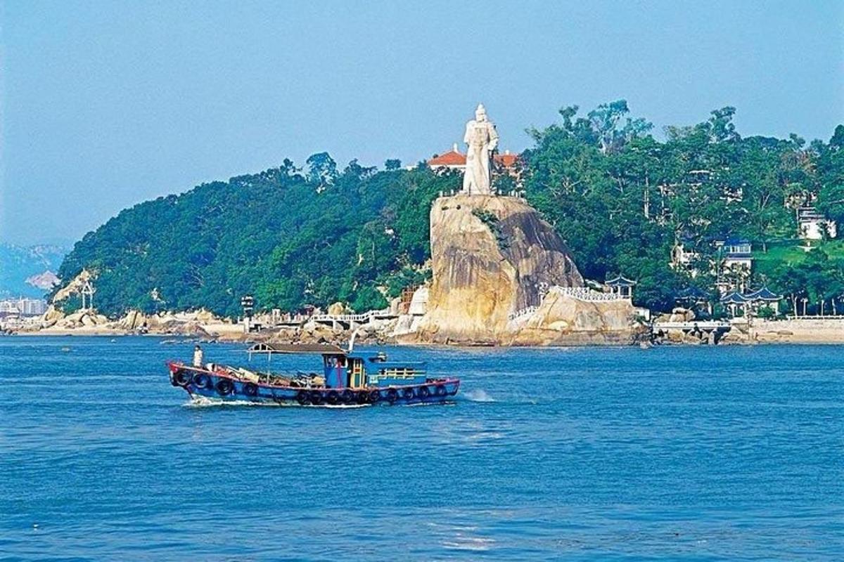 a boat in the water with a statue in the background