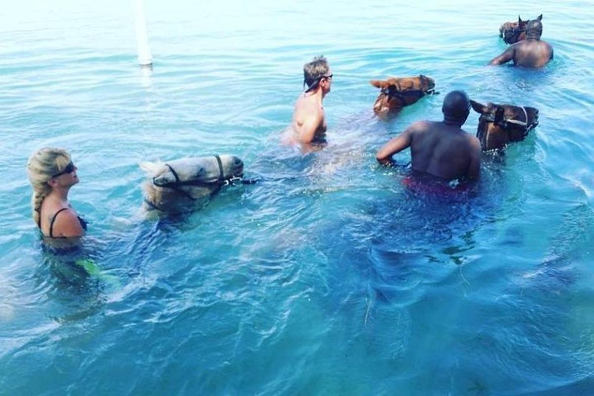un gruppo di persone in acqua con i cavalli