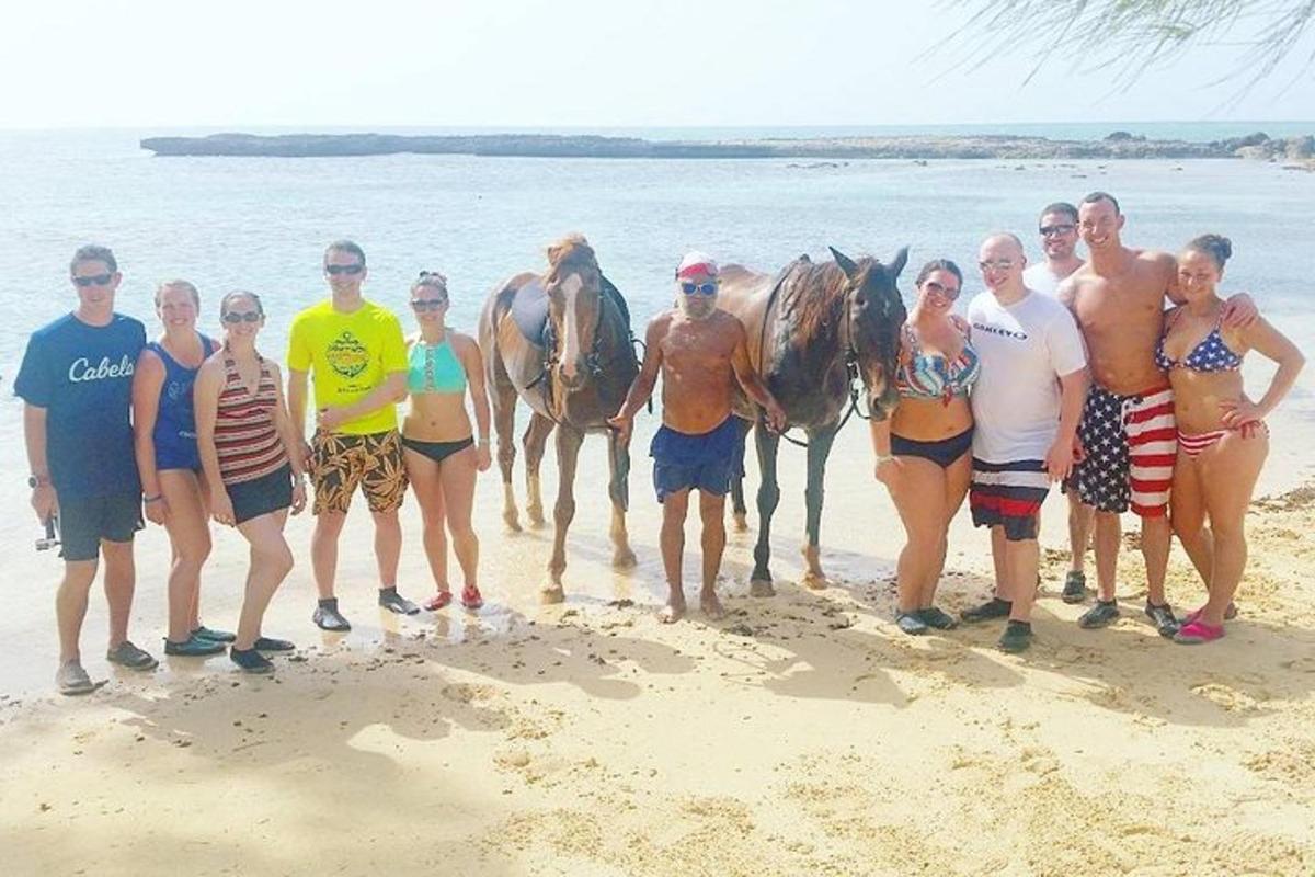 skupina ljudi, ki stojijo na plaži s konji