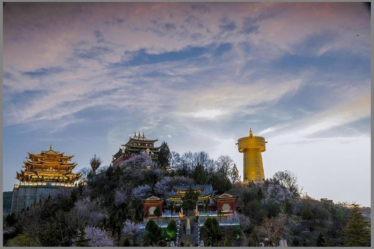 a yellow lighthouse on a hill with buildings in the background
