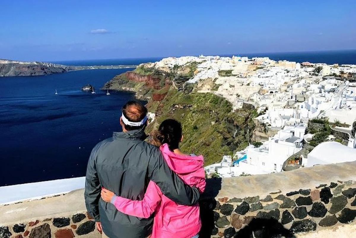 a man and a woman sitting on a ledge looking out over the ocean