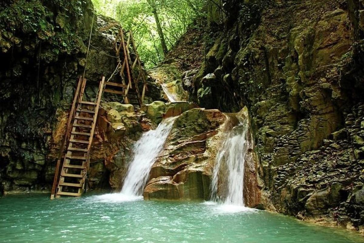 a waterfall in the middle of a mountain with a ladder