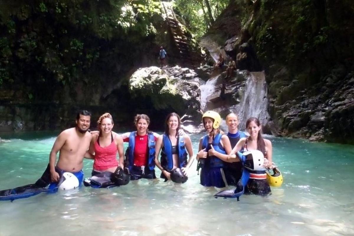 a group of people in the water in front of a waterfall