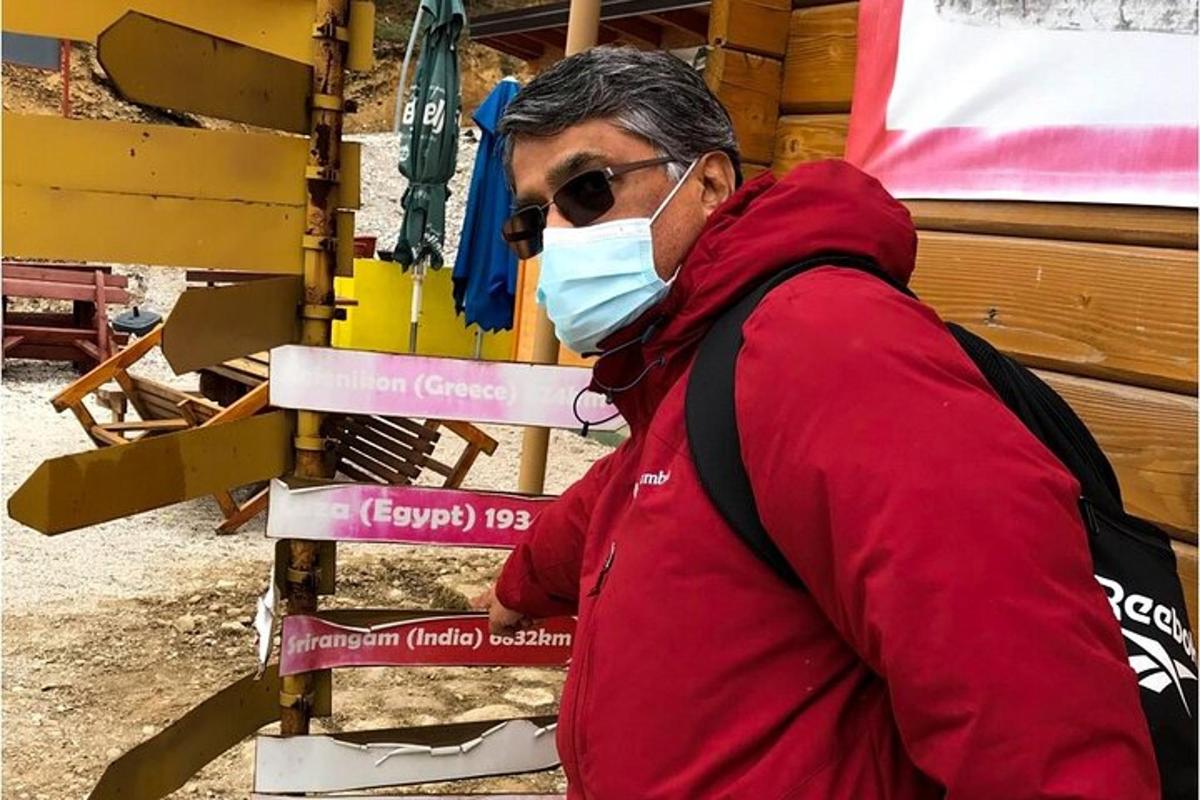 um homem usando uma máscara em pé ao lado de uma placa