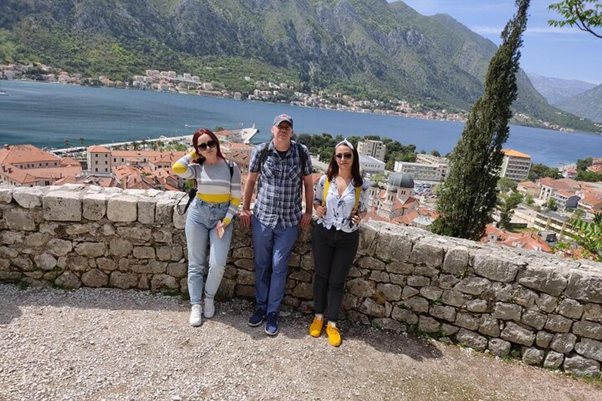 tres persones dempeus al costat d'un mur de pedra
