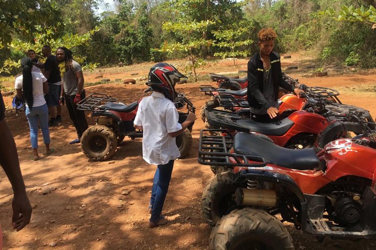 a group of people standing around atvs on a dirt road