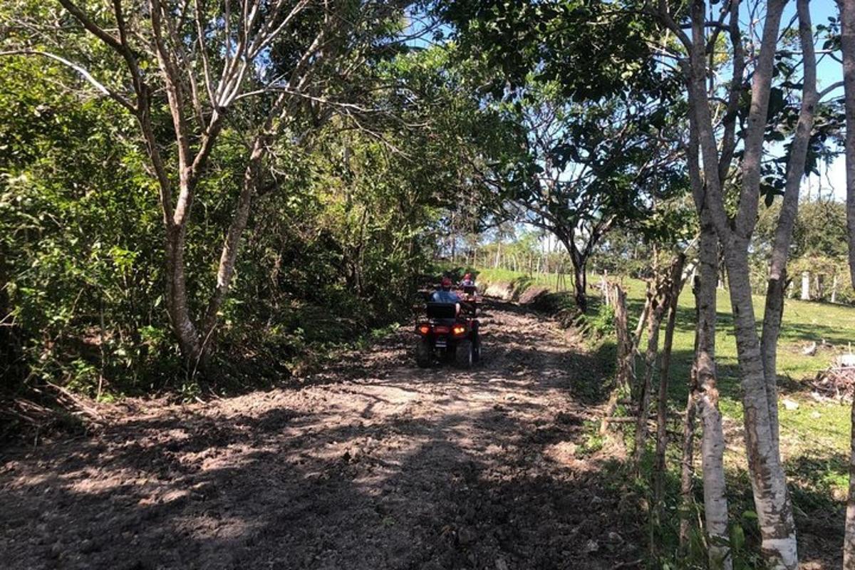 two people riding a motorcycle down a dirt road