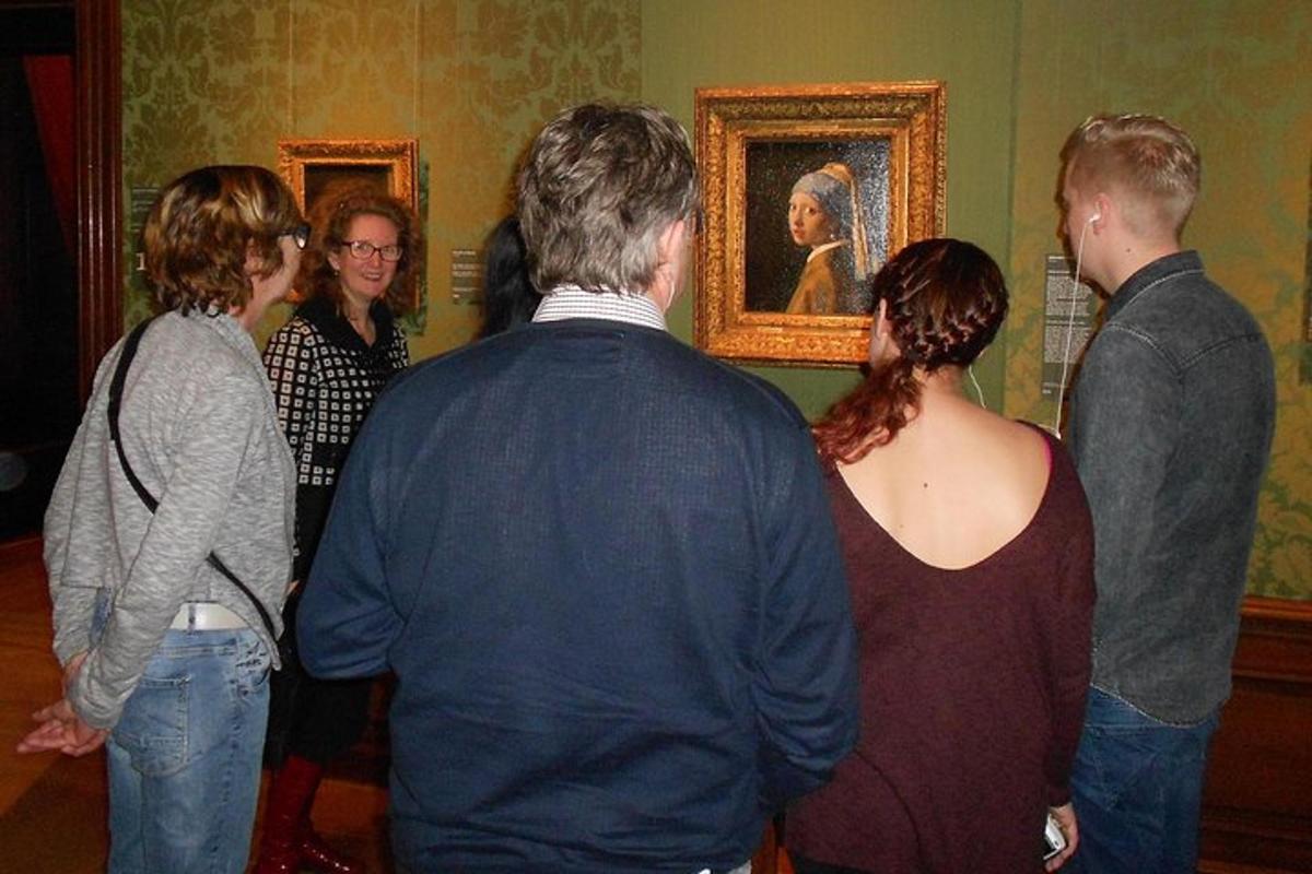 Un grupo de personas de pie en una habitación mirando una pintura.