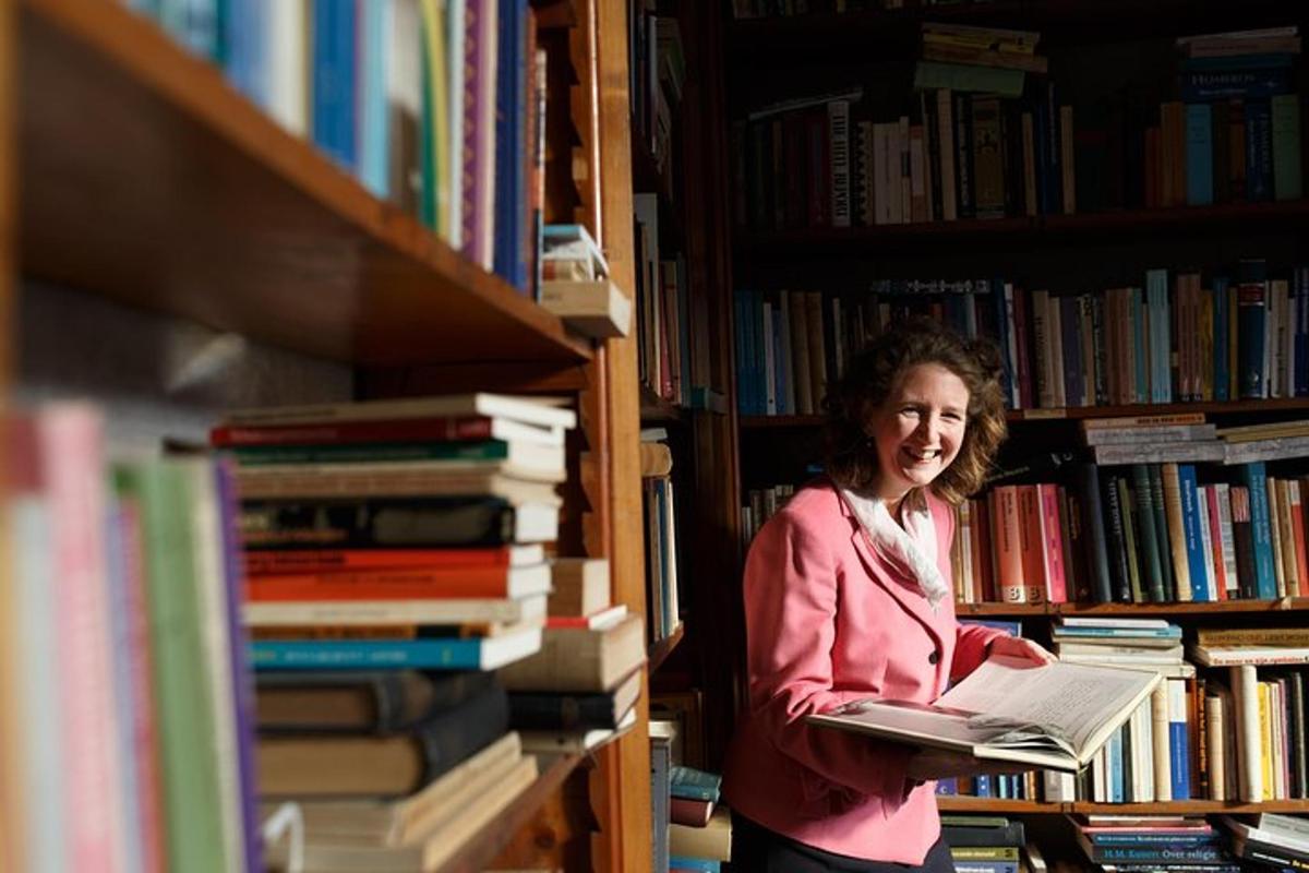 a woman standing in a library holding a book