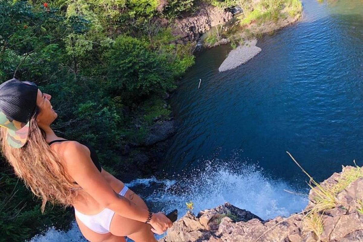 Una mujer parada en un acantilado mirando hacia un río.