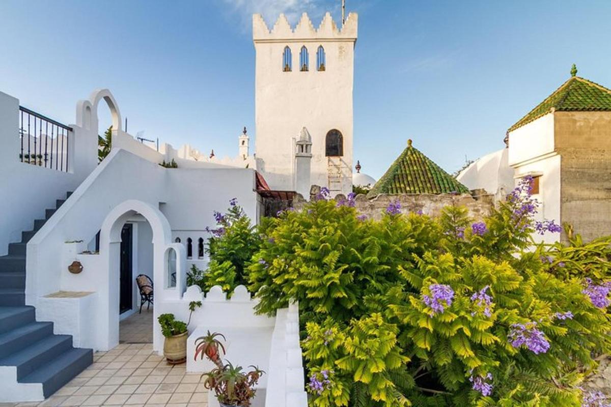 un edificio bianco con una torre dell'orologio e fiori viola