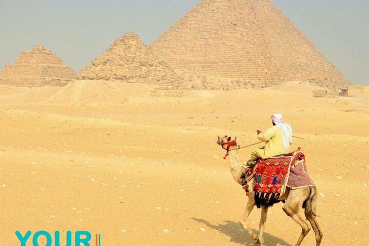 a man riding a camel in front of the pyramids