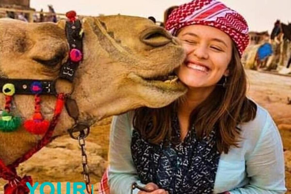 a woman is kissing a camel