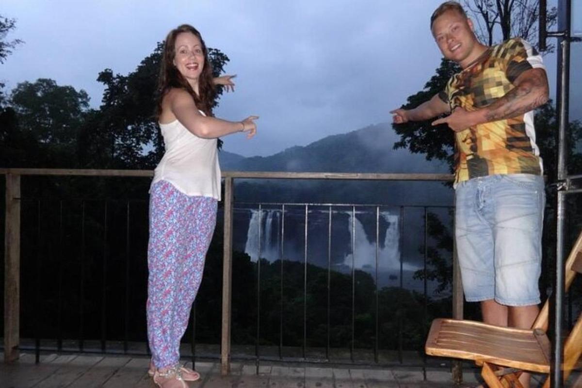 a man and a girl standing on a balcony with a view of niagara