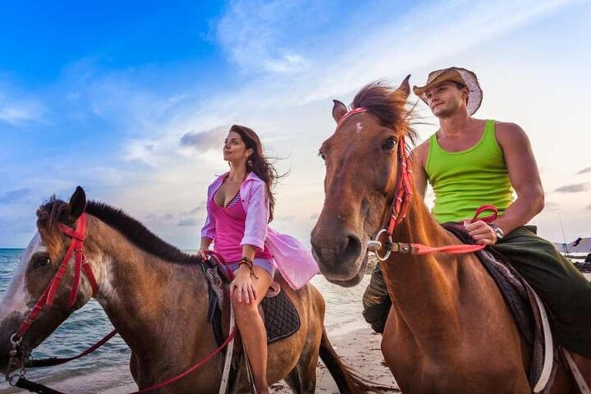 a man and a woman riding horses on the beach