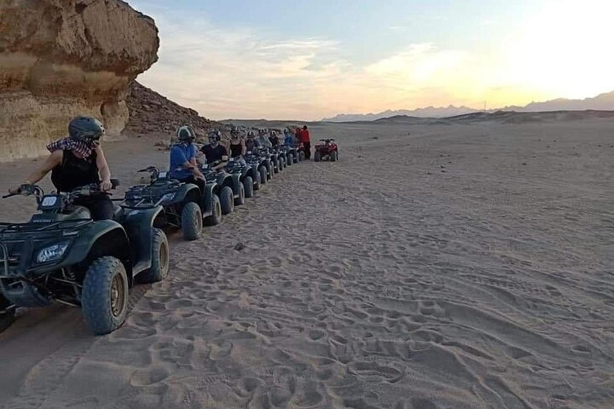 um grupo de pessoas andando de quadriciclo no deserto