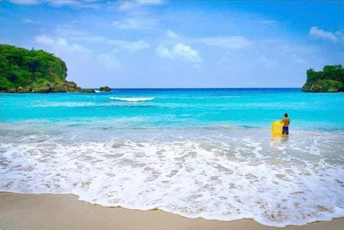 un uomo in piedi nell'oceano con una tavola da surf gialla