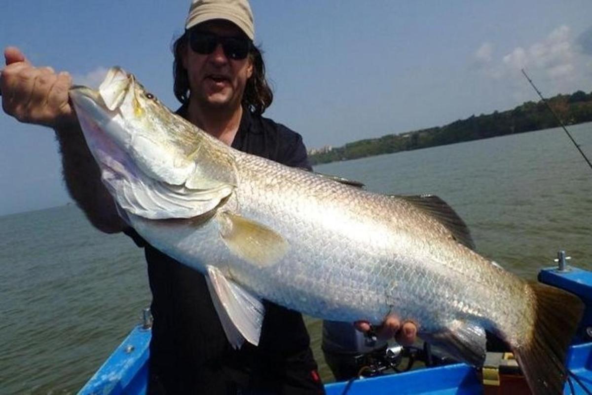 isang lalaking may hawak na malaking isda sa isang bangka