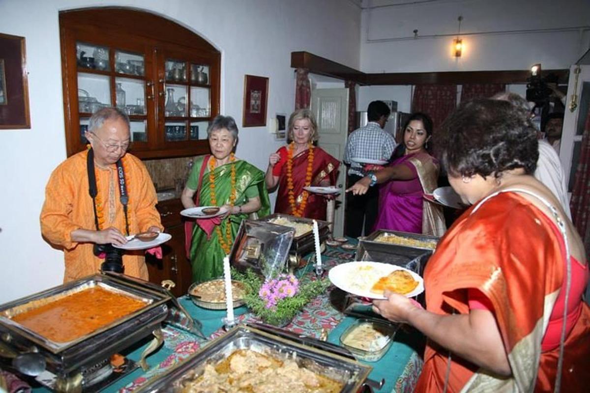 a group of people standing around a table with food